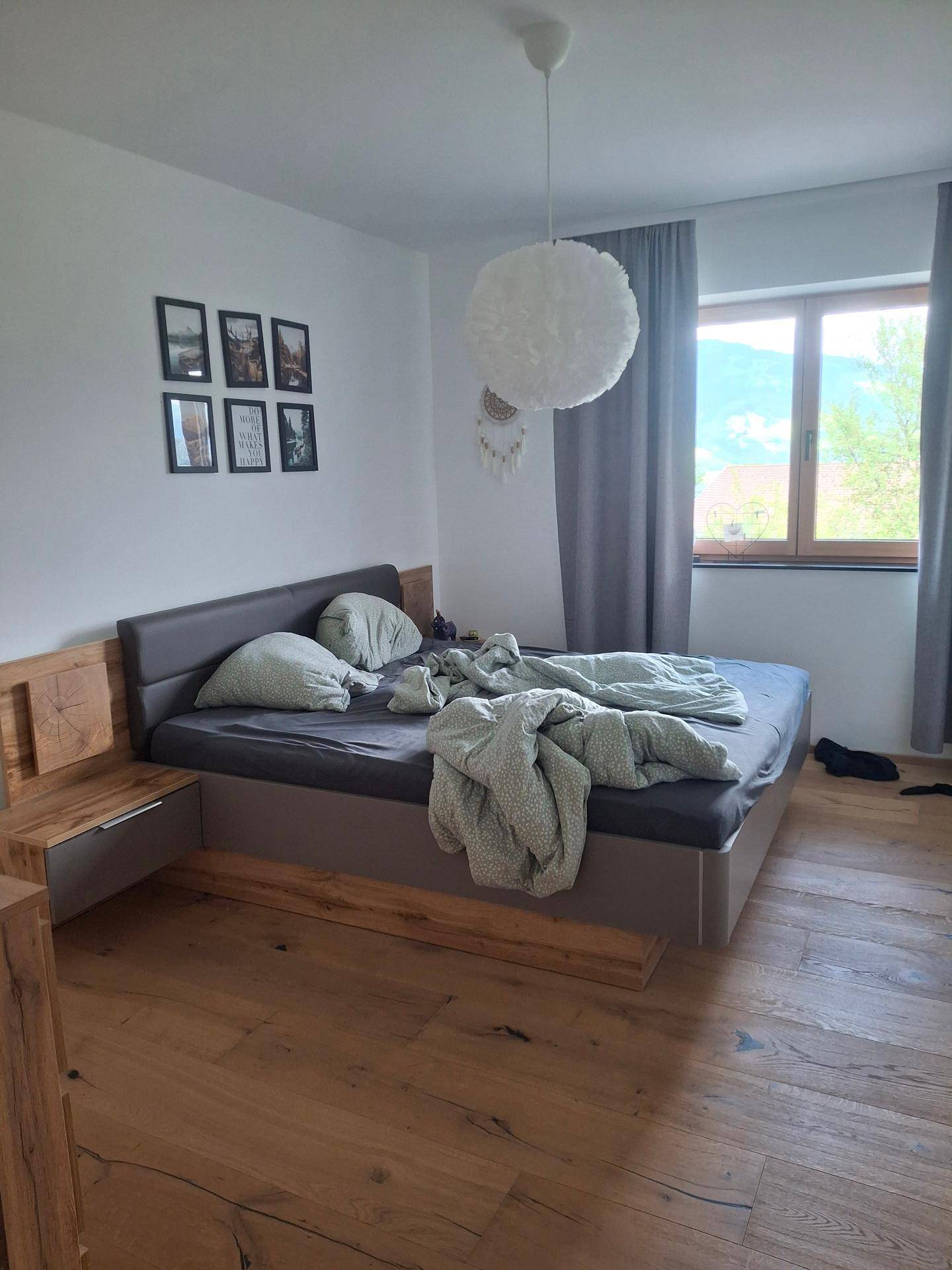 Schlafzimmer mit Doppelbett, Holzboden und Fenster mit Blick auf die umliegende Landschaft.