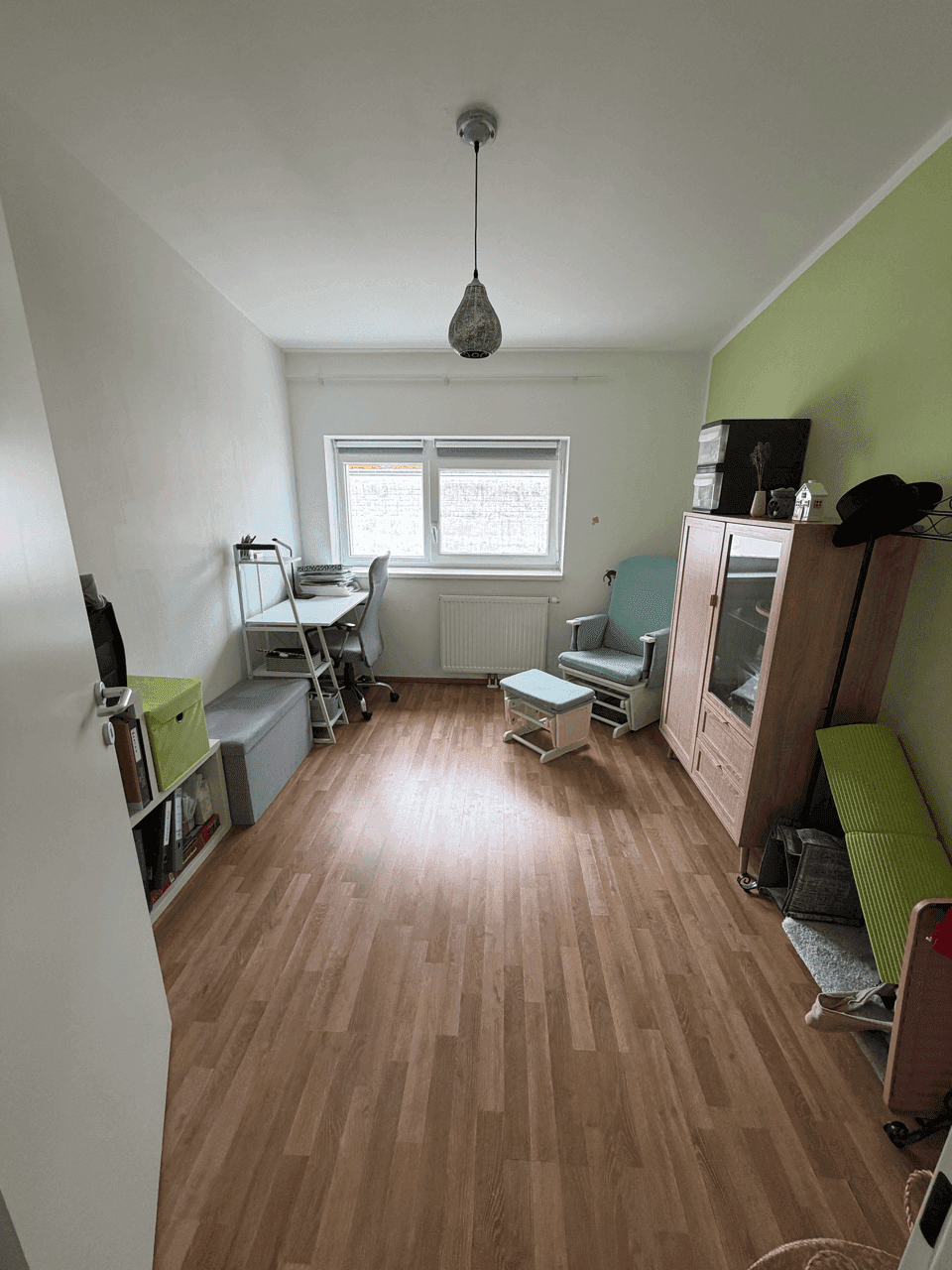 Helles Zimmer, eingerichtet als Büro oder Gästezimmer, mit Schreibtisch und Laminatboden.