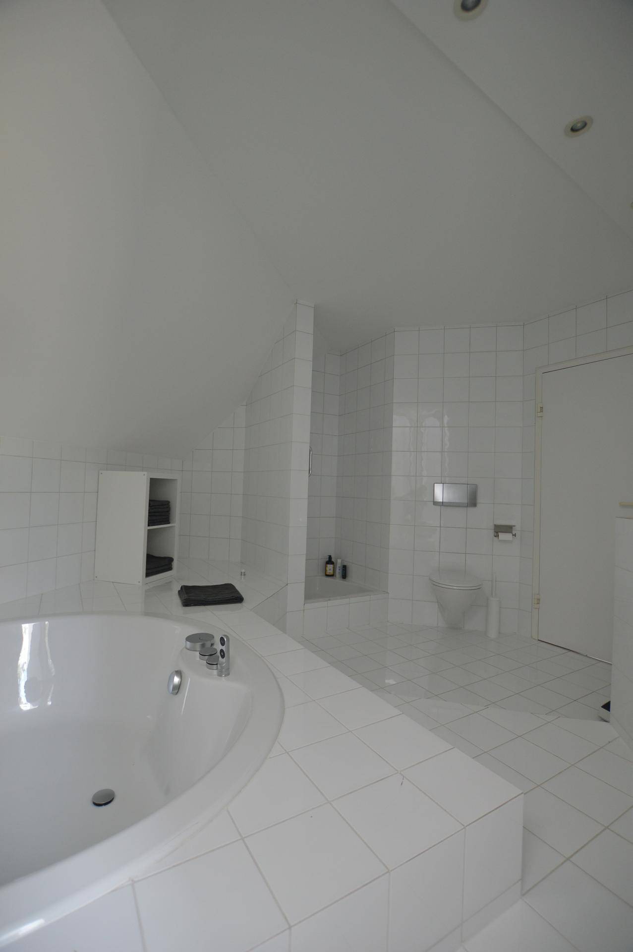 Geräumiges Badezimmer im Dachgeschoss mit Badewanne, WC und weißen Fliesen.