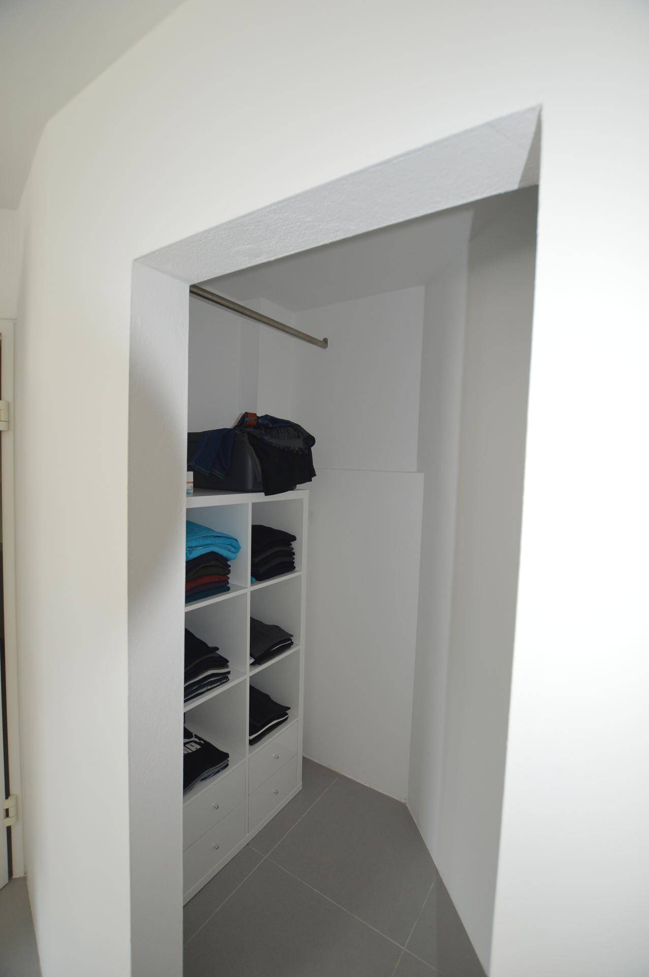Praktischer begehbarer Kleiderschrank mit Regalen und Kleiderstange.