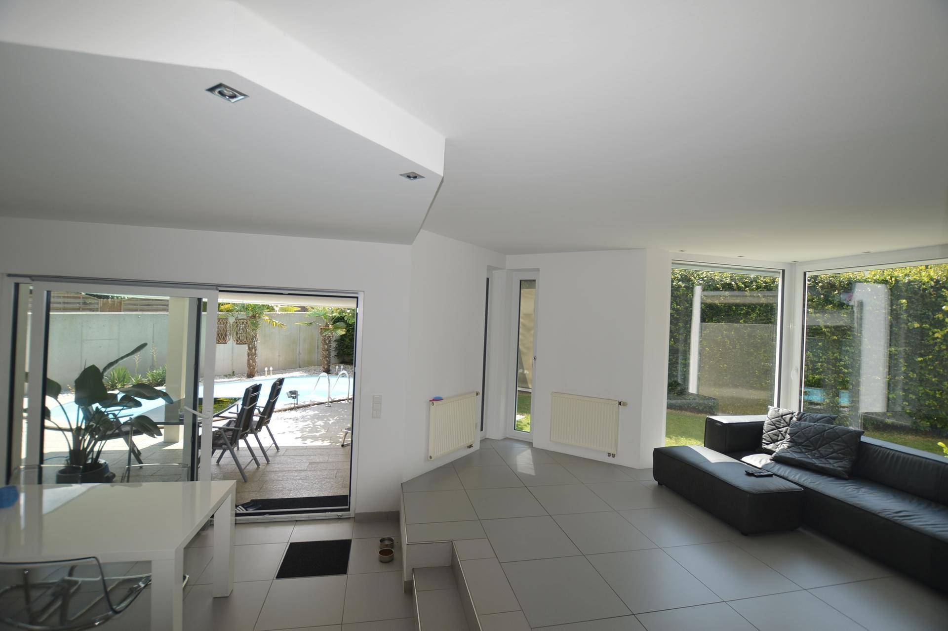 Geräumiges Wohnzimmer mit Blick auf den Poolbereich und Zugang zur Terrasse.