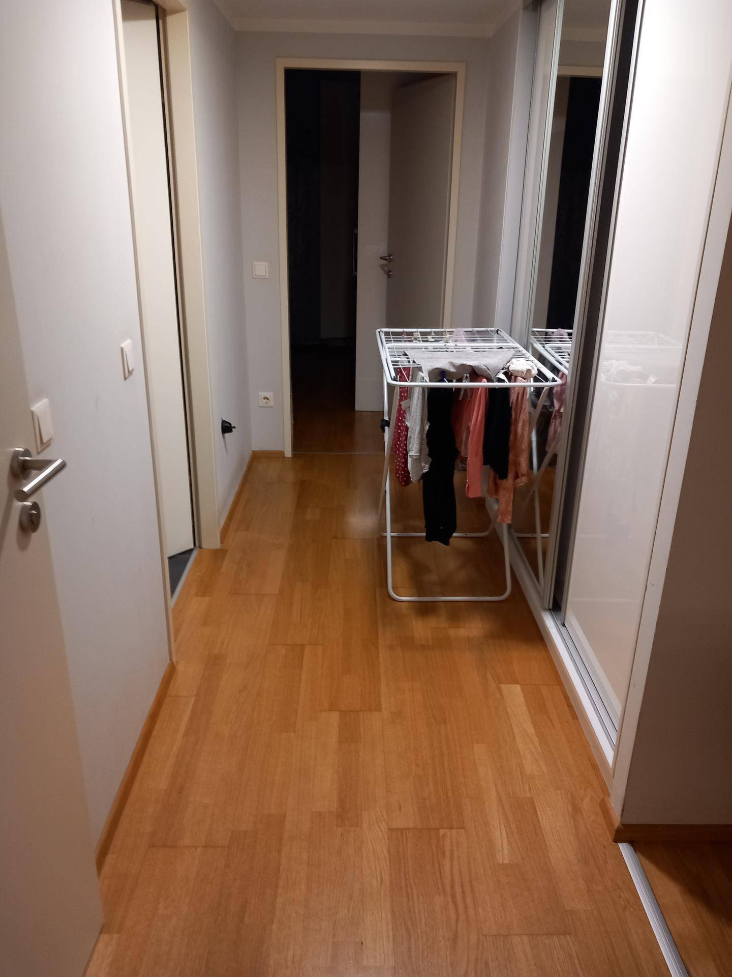 Langer Flur mit Laminatboden, Schiebetürenschrank und einem Wäscheständer.