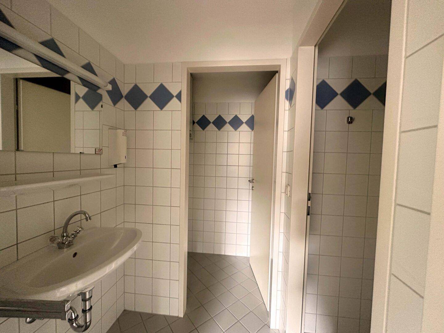 Badezimmer mit Waschbecken, Spiegel und weiß-blauen Fliesen, die einen sauberen Eindruck machen.