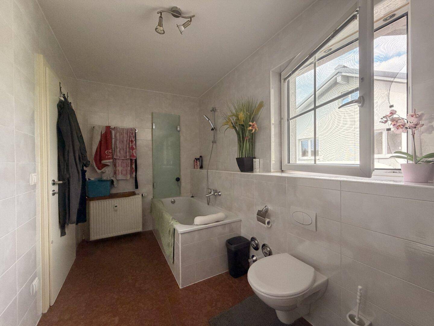 Helles Badezimmer mit Badewanne, WC, Waschbecken und einem großen Fenster im Dachgeschoss.