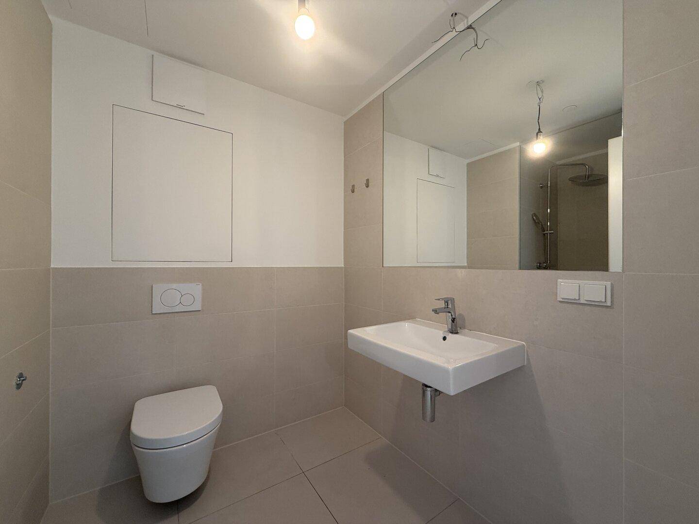 Modernes Badezimmer mit wandhängendem WC, Einzelwaschbecken und großem Spiegel.