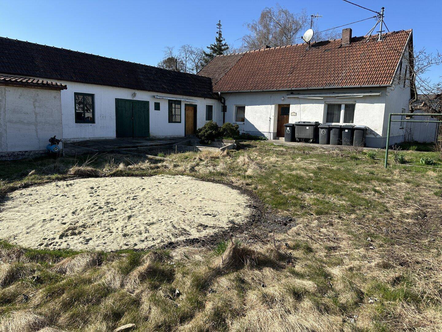 Hinteransicht des Hauses mit großem Gartenbereich und einer vorbereiteten Fläche im Vordergrund.