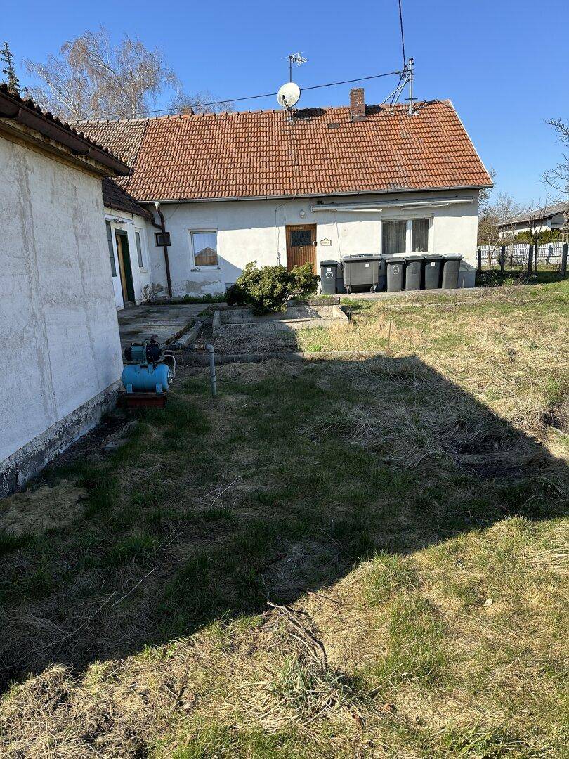 Weitläufiger Blick auf die Rückseite des Hauses mit Gartenfläche und sichtbarer Wasserpumpe.