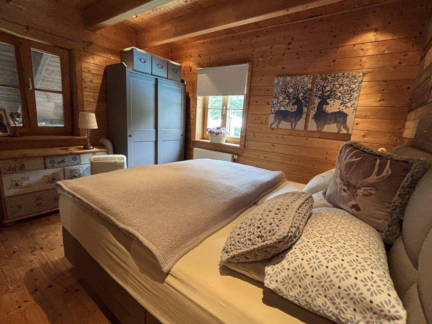 Gemütliches Schlafzimmer mit Holzwänden, Doppelbett und rustikalen Dekorationselementen.