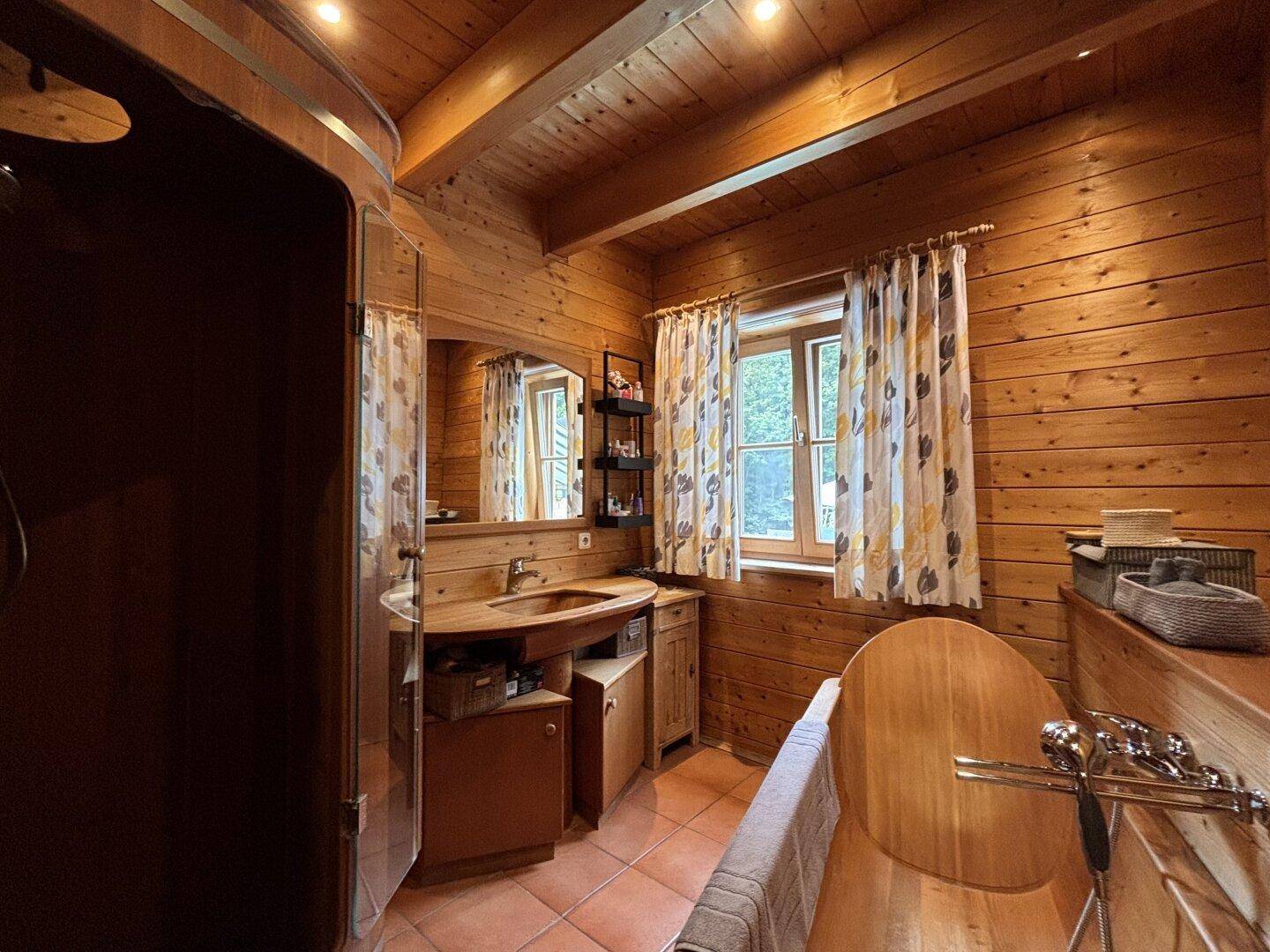 Rustikales Badezimmer mit Holzelementen, Badewanne und Terrakotta-Fliesenboden.