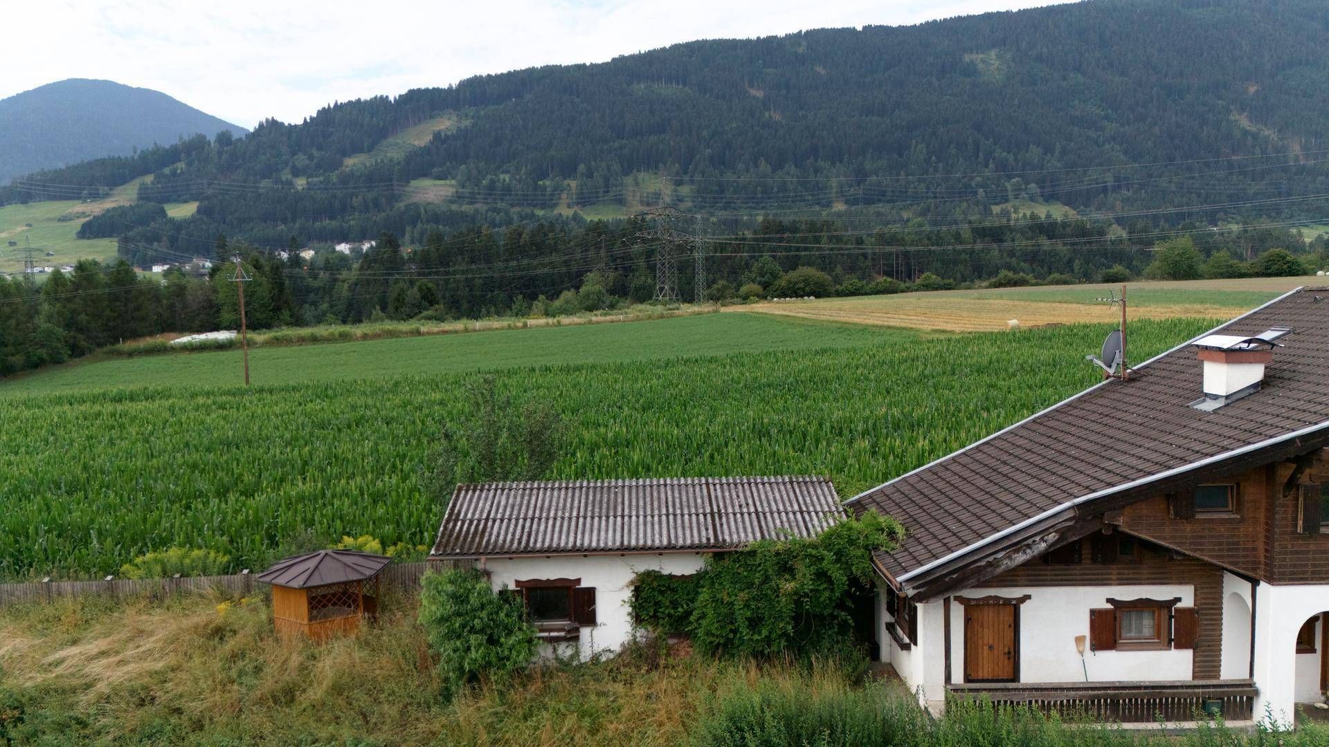 Traditionelles Haus mit braunem Dach und einem weiten grünen Feld im Hintergrund.