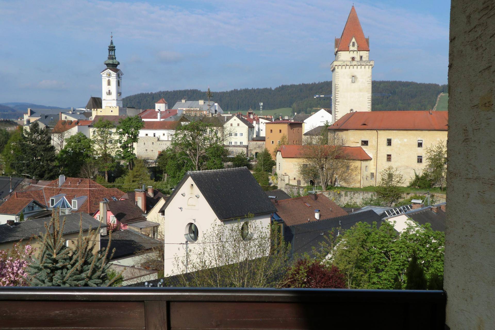 Aussicht von einem Balkon auf die historische Stadt mit Kirchturm und Burgturm.