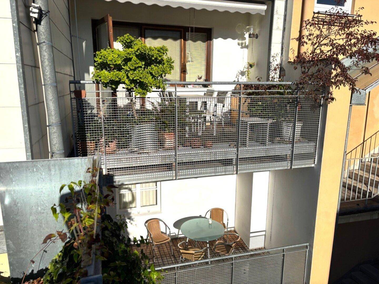 Mehrere Balkone mit Metallgeländern, bepflanzt und mit Sitzgelegenheiten ausgestattet.