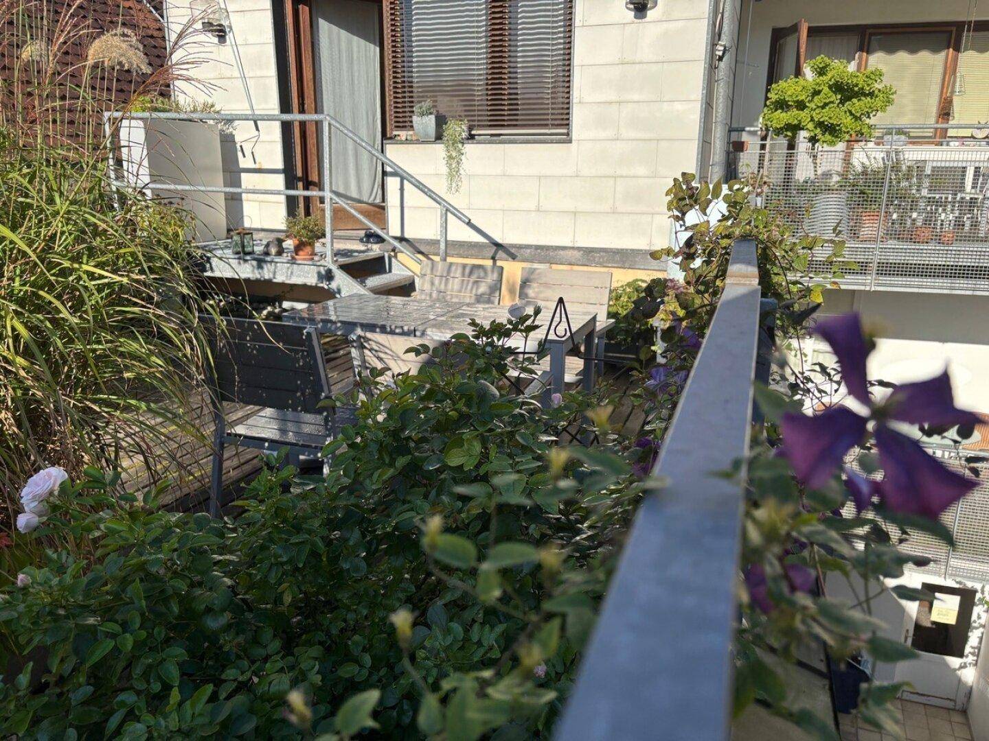 Grüne Terrasse mit üppiger Bepflanzung und einer Treppe, die zu einem weiteren Bereich führt.