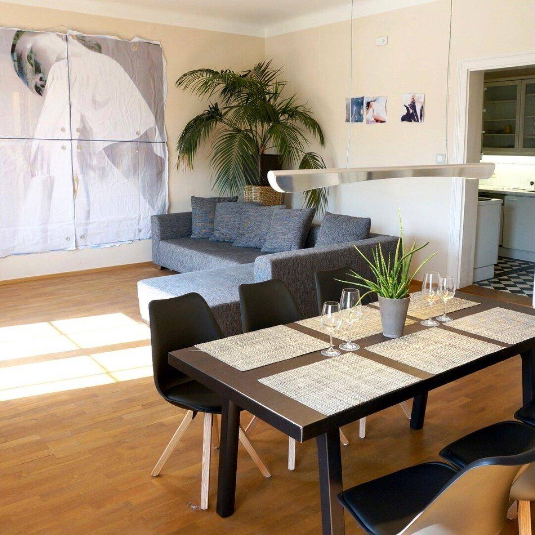 Offener Wohn-Essbereich mit Holzboden, Sofa und integrierter Küchenzeile.
