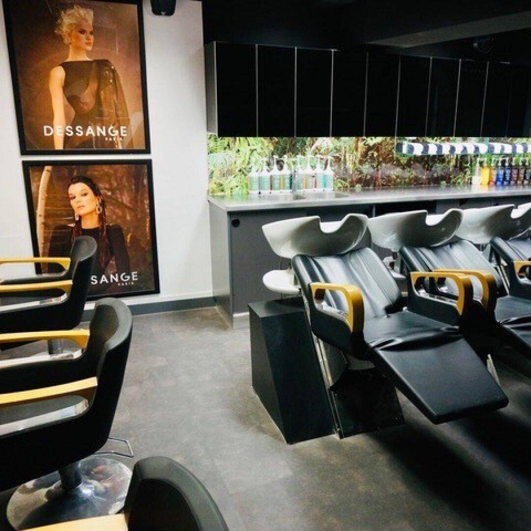 Friseursalon mit Waschplätzen, schwarzen Schränken und modernen Stühlen.