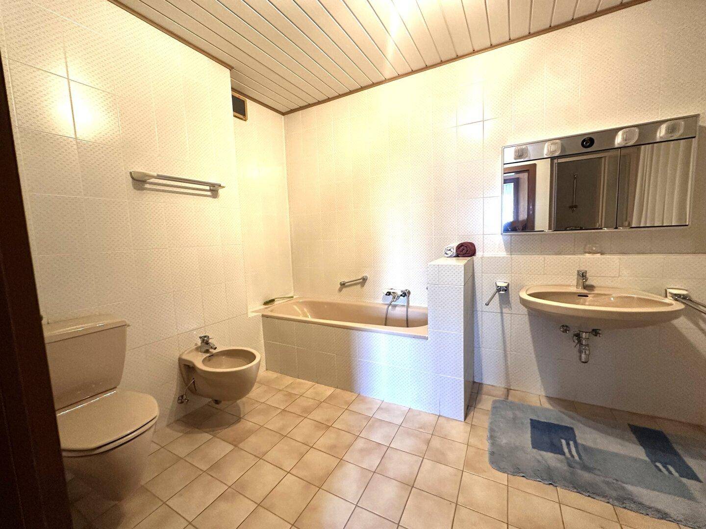 Klassisches Badezimmer mit Badewanne, Bidet und Waschbecken, ausgestattet mit Fliesenboden.