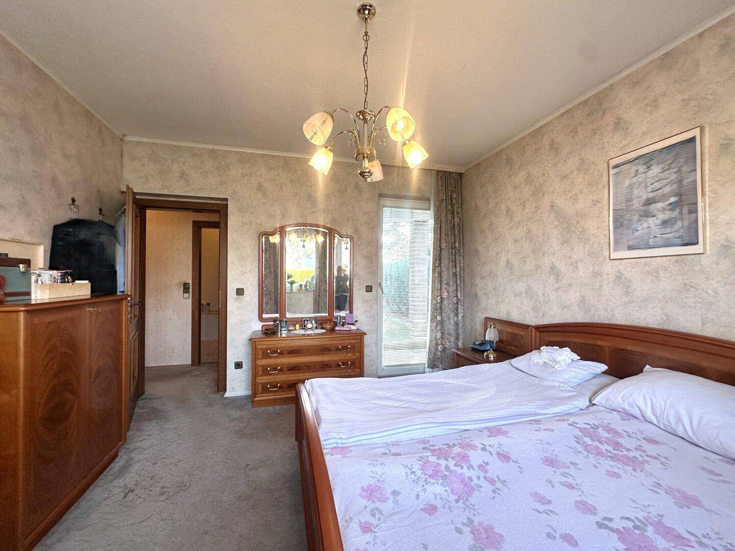 Gemütliches Schlafzimmer mit Doppelbett, Teppichboden und traditionellen Holzmöbeln.