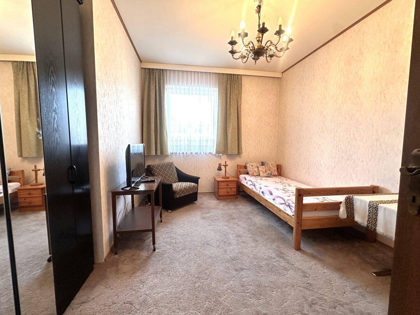 Traditionelles Schlafzimmer mit Einzelbett, Teppichboden und klassischer Einrichtung.