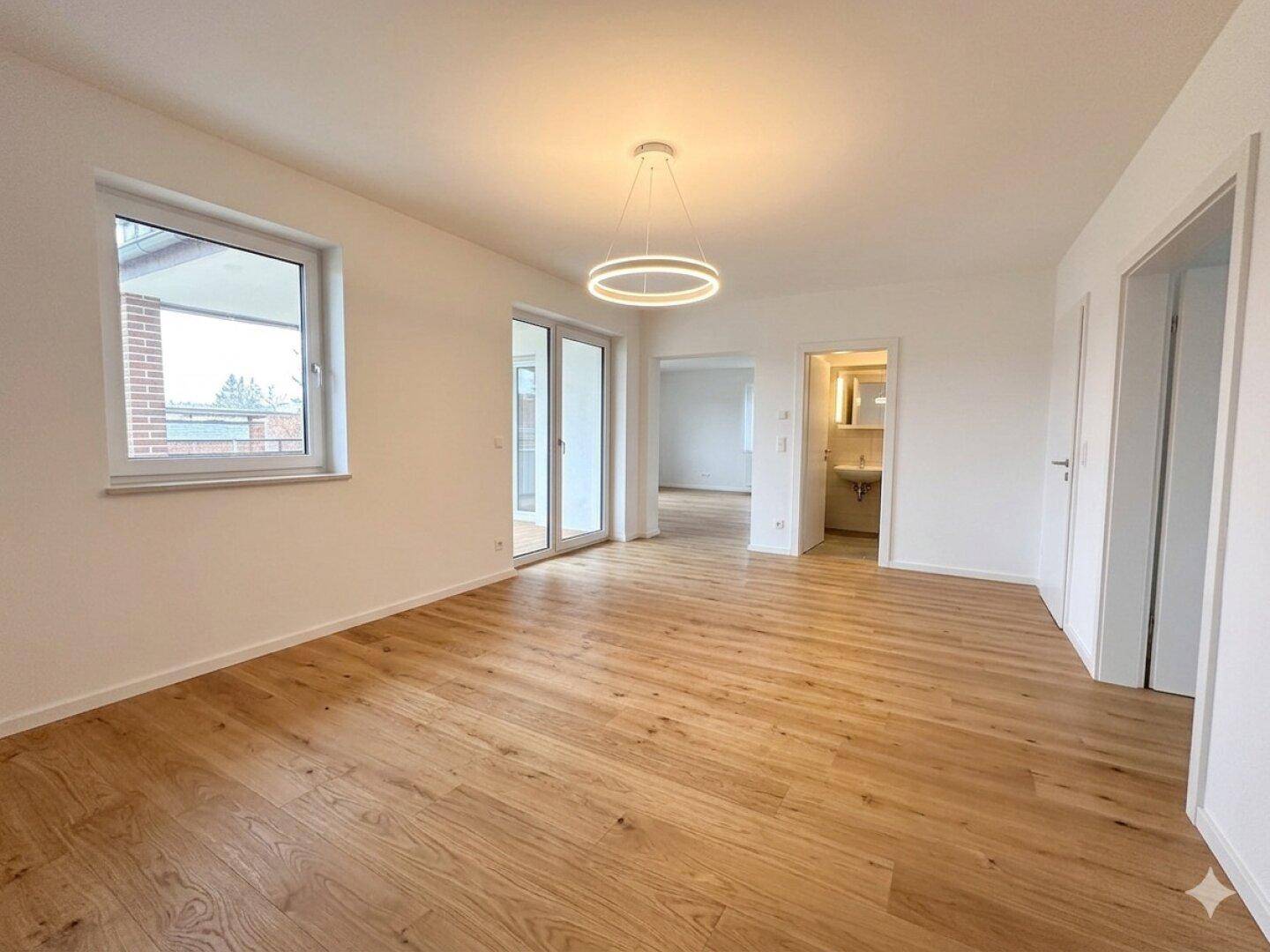 Helles, leeres Zimmer mit neuem Holzboden und großen Fenstern, bereit zur individuellen Gestaltung.