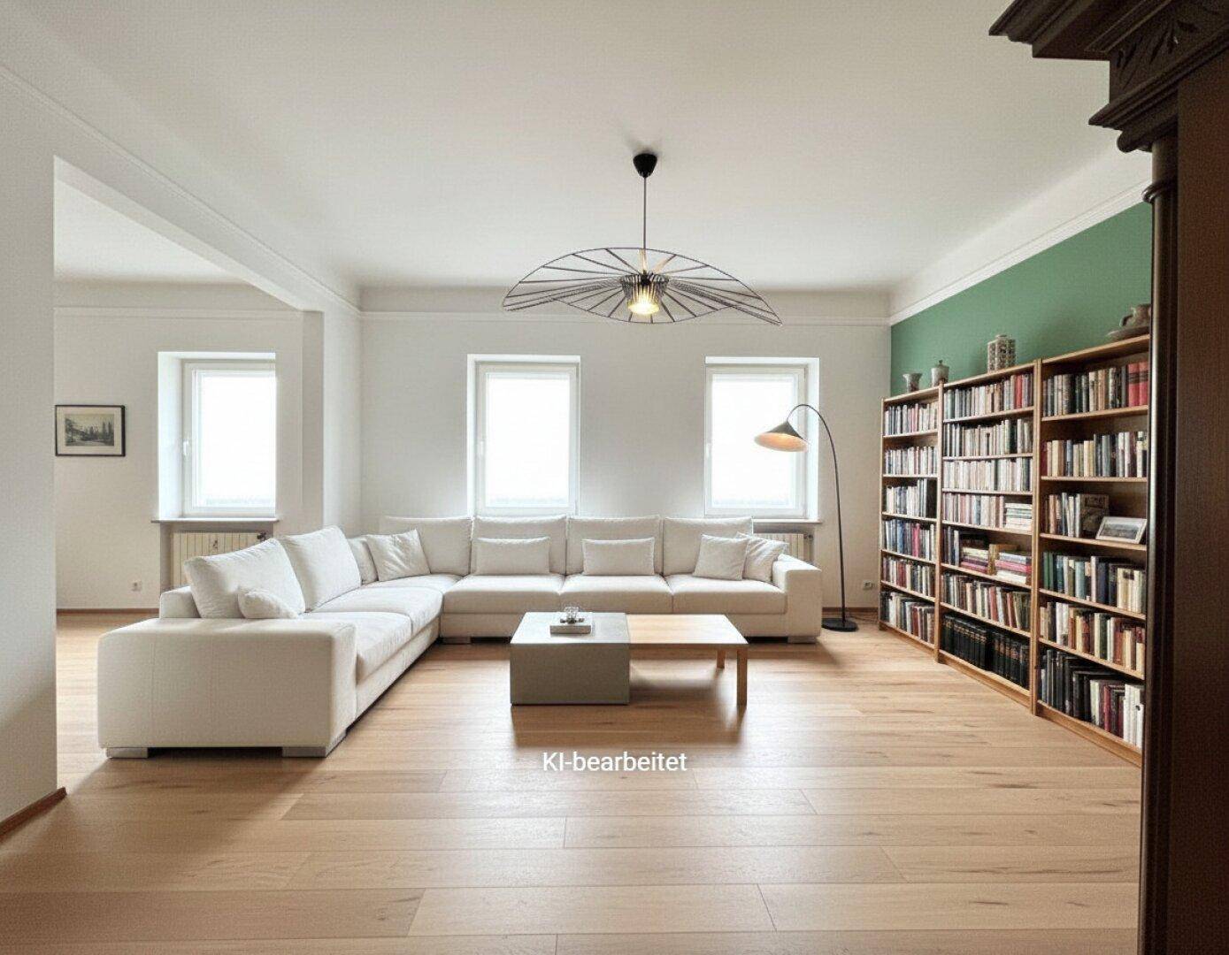 Helles Wohnzimmer mit Eichenparkett, großem Ecksofa und Bücherregal an der grünen Wand.