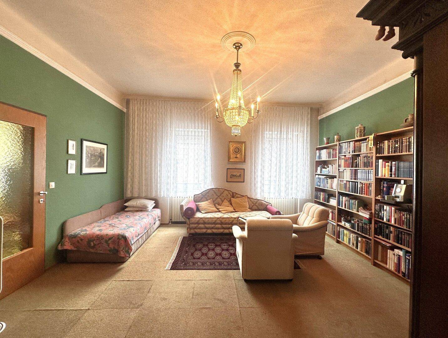 Gemütliches Wohnzimmer mit Teppichboden, Kronleuchter und traditionellen Möbeln.