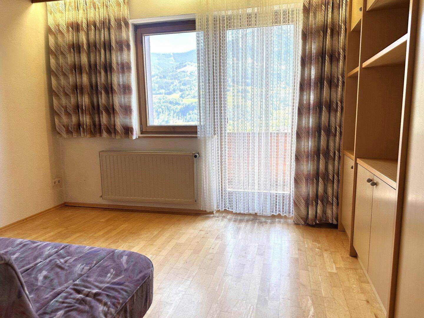Helles Schlafzimmer mit Parkettboden, Holzdecke und Fenster, das einen angenehmen Ausblick bietet.