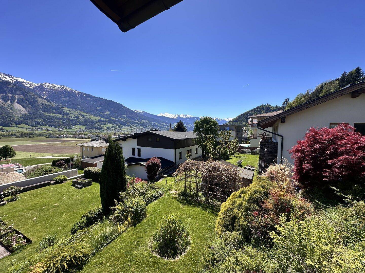 Weitläufiger Blick auf die umliegende Berglandschaft und grüne Natur an einem sonnigen Tag.