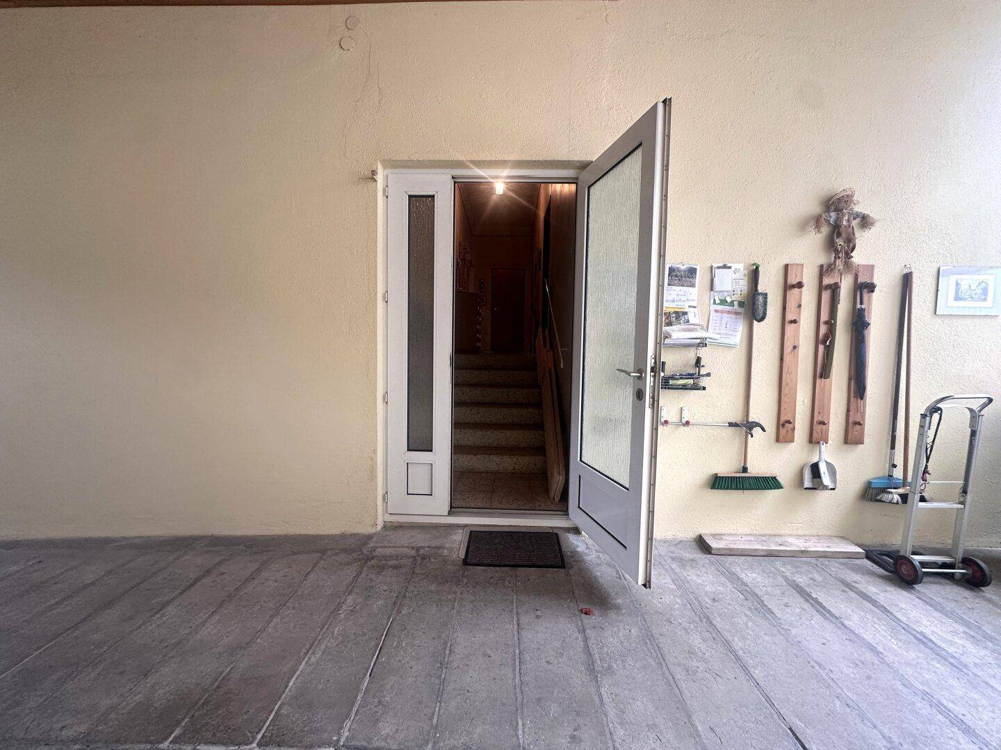 Funktionaler Abstellraum mit Holzdecke, verschiedenen Werkzeugen und Zugang zum Treppenhaus.