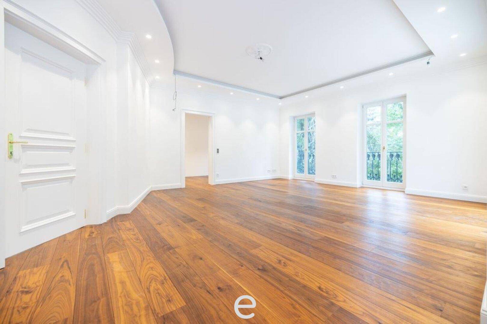 Geräumiger Wohnraum mit französischem Balkon und elegantem Holzparkettboden.