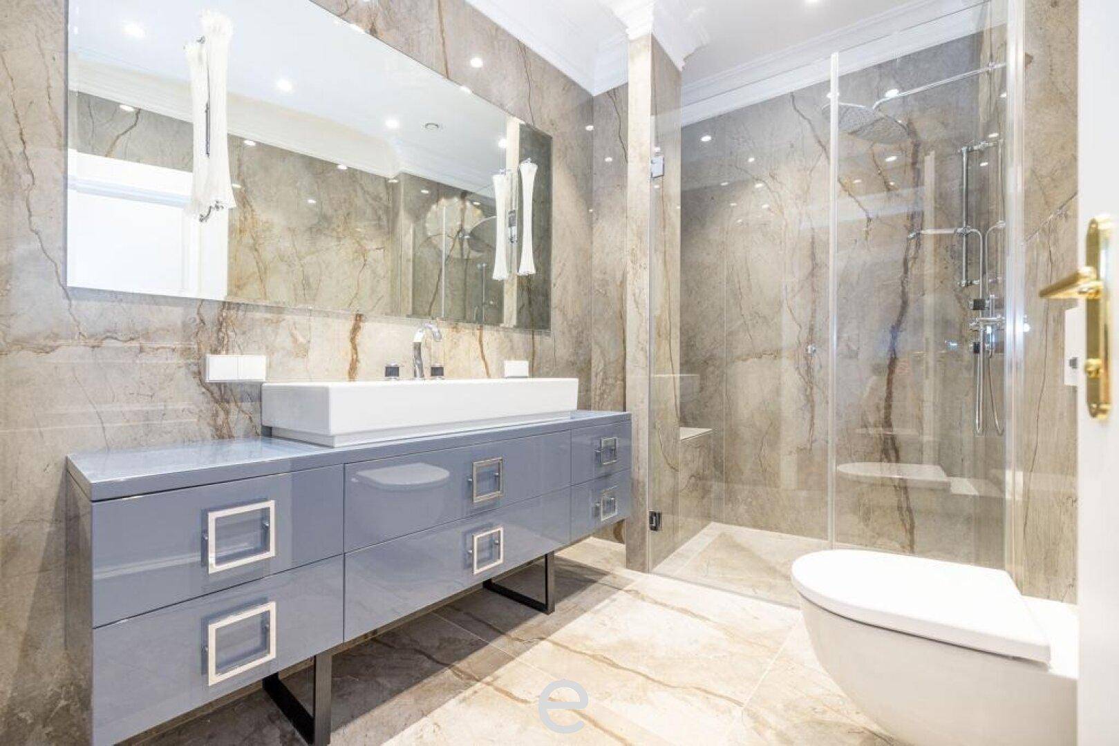 Modernes Badezimmer mit begehbarer Dusche, stilvollem Waschtisch und Marmorfliesen.