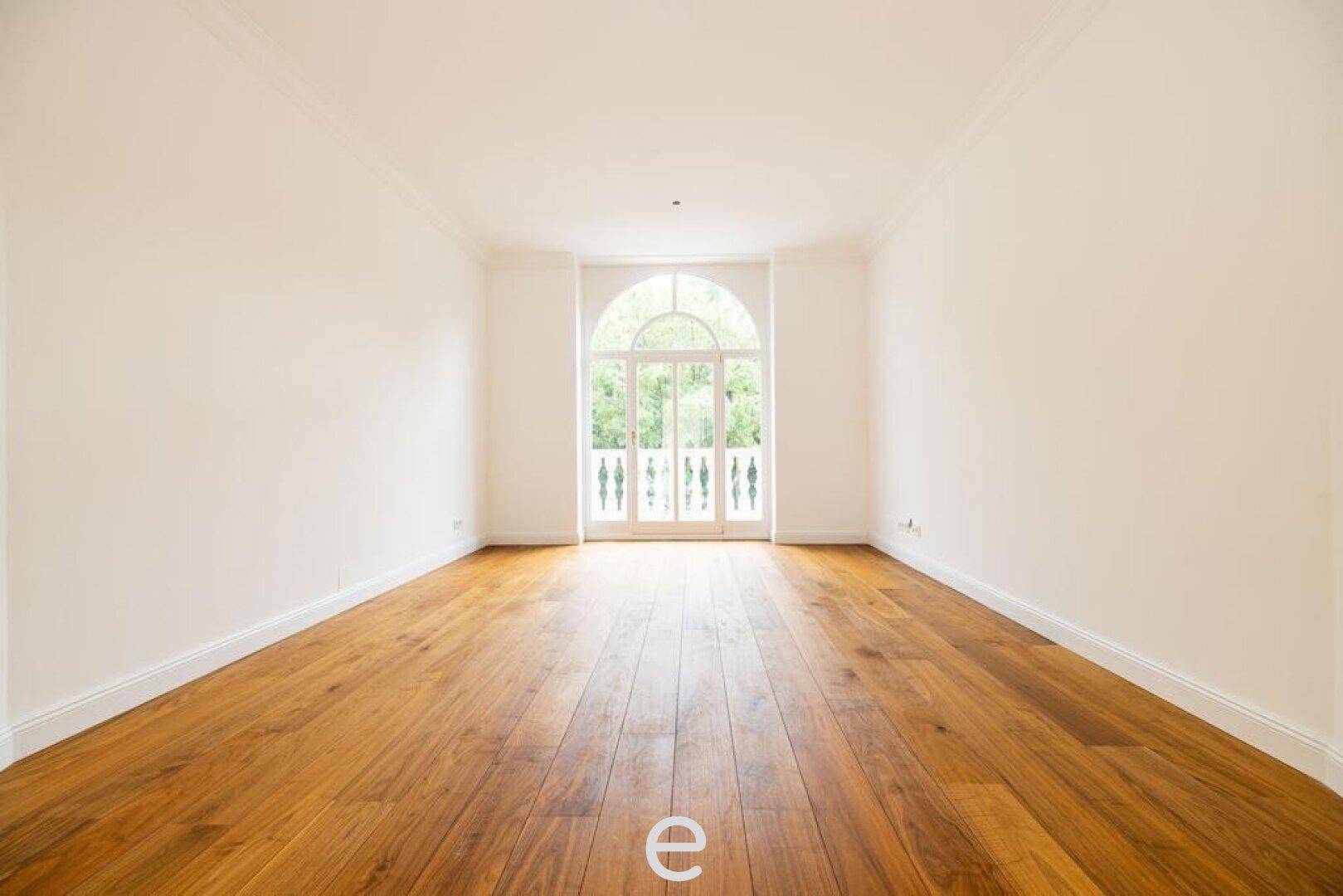 Heller Raum mit französischem Balkon und hochwertigem Holzparkettboden.