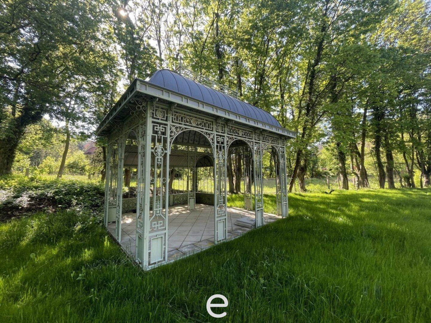 Detailansicht des kunstvollen Pavillons im weitläufigen, grünen Garten.
