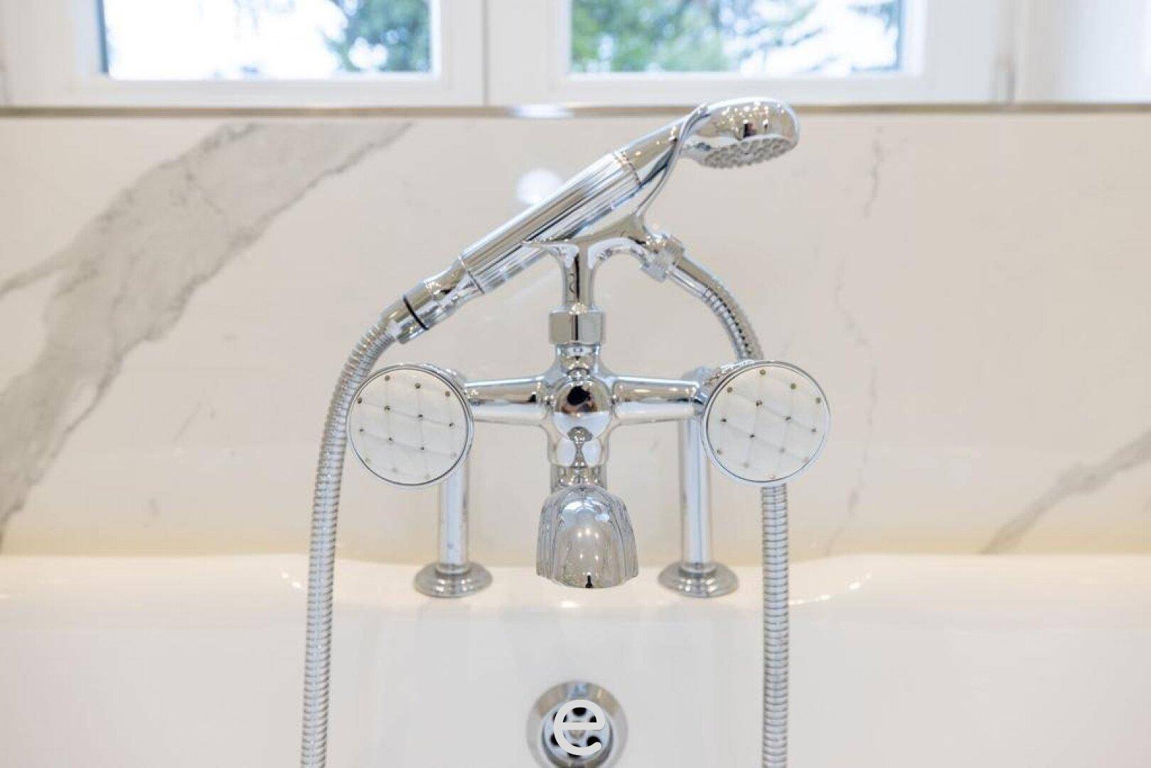 Detailaufnahme der eleganten Armaturen an der freistehenden Badewanne im Marmorbad.