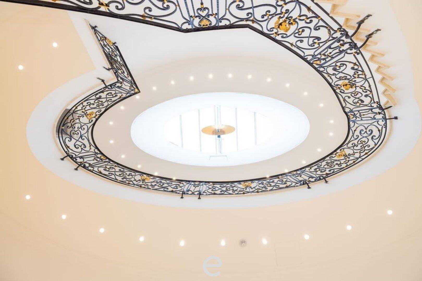 Elegantes Treppenhaus mit kunstvollem schmiedeeisernem Geländer und Oberlicht.