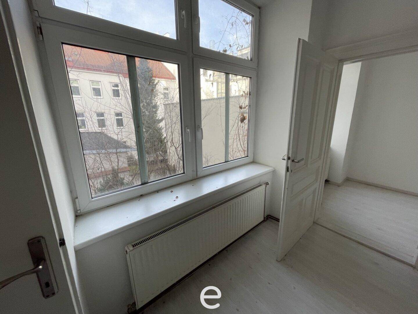 Heller Raum mit großem Fenster, Blick in den Innenhof und Heizkörper unter dem Fensterbrett.