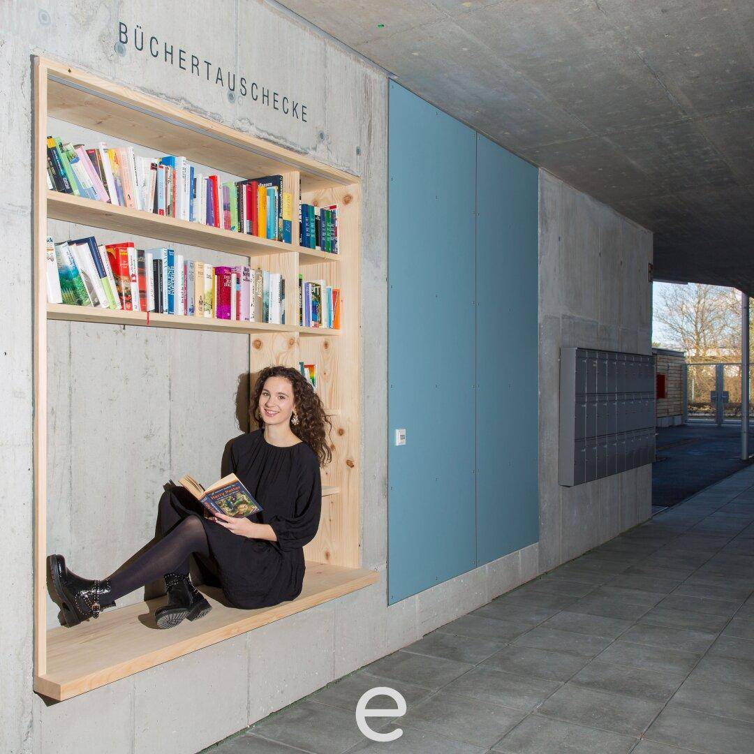 Gemeinschaftsbereich mit Bücherregal und Sitzgelegenheit für Bewohner.