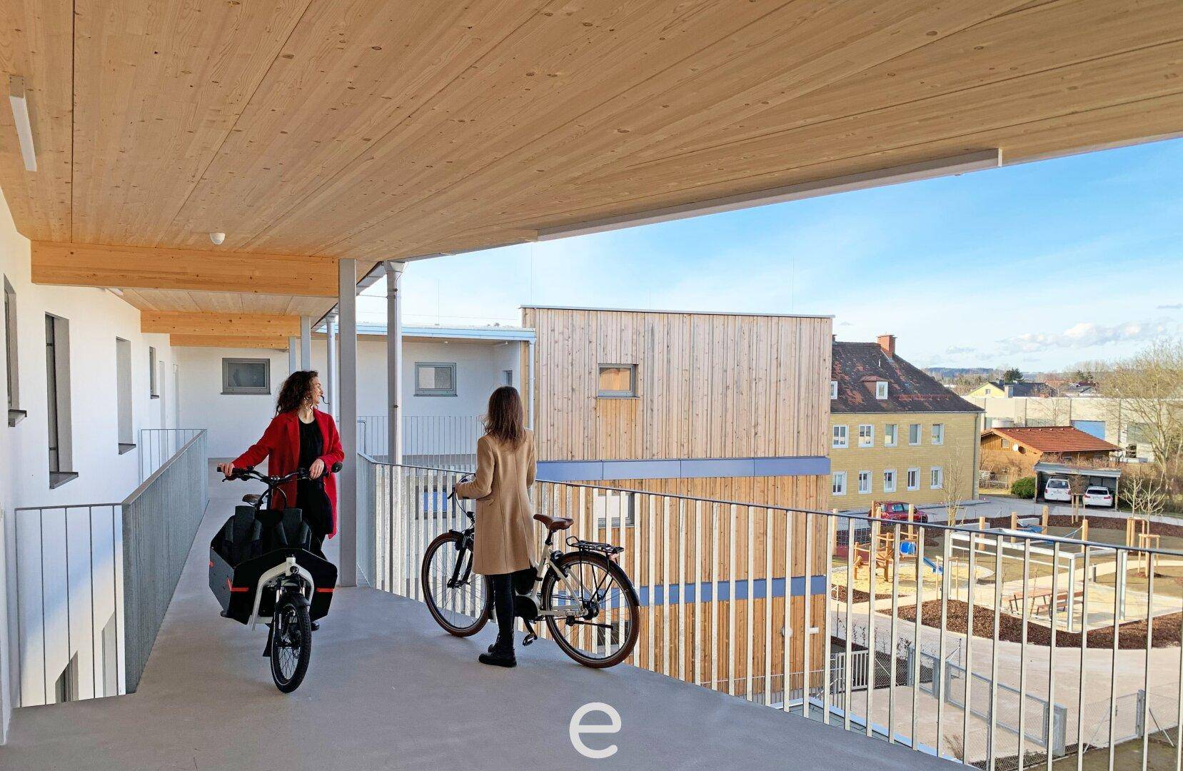 Heller Laubengang mit Holzdecke und Ausblick auf den Innenhof und die Umgebung.