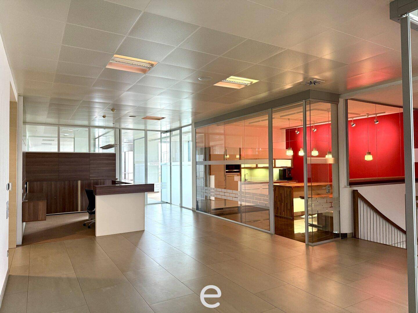 Geräumiger Bürobereich mit Empfangstheke, integrierter Küchenzeile und Zugang zu weiteren Büros.