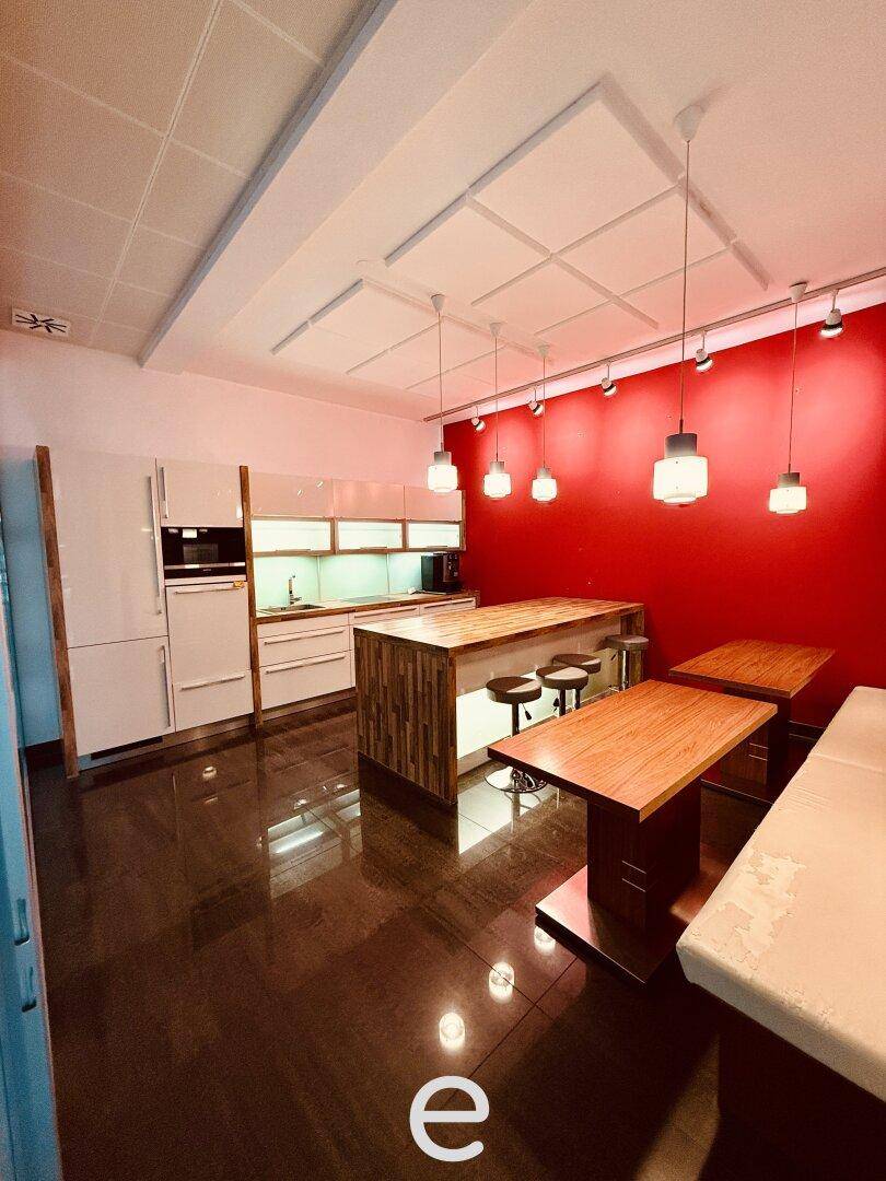 Moderne Küche mit roten Wänden, weißen Hochglanzschränken und einer Holzinsel mit Barhockern.