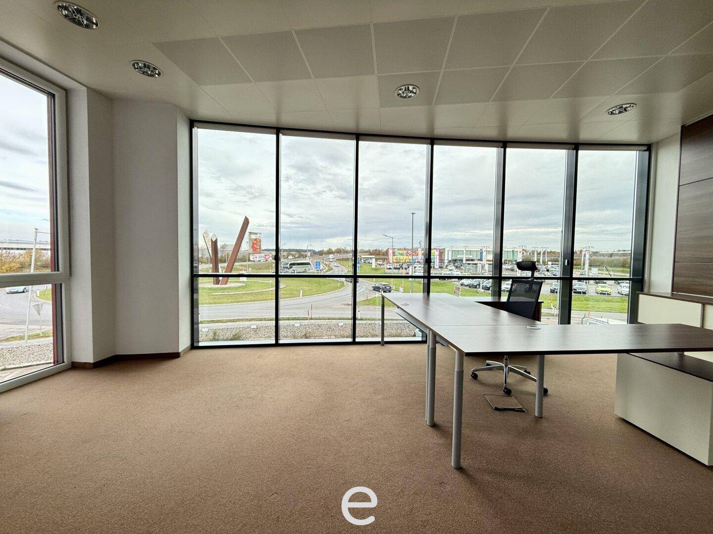 Helles Büro mit großen Fenstern, die einen weiten Blick auf die Umgebung und eine Straße bieten.