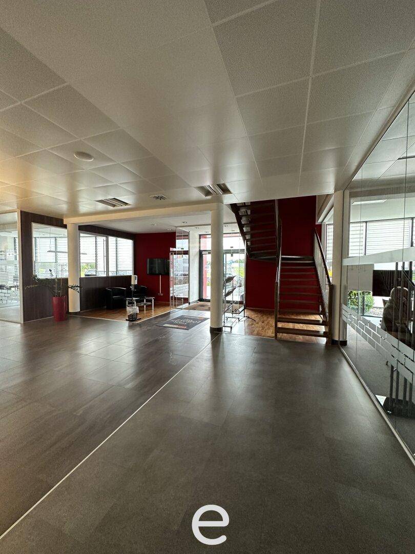 Offener Bürobereich mit dunklem Boden, einer markanten roten Wand und einer Holztreppe.