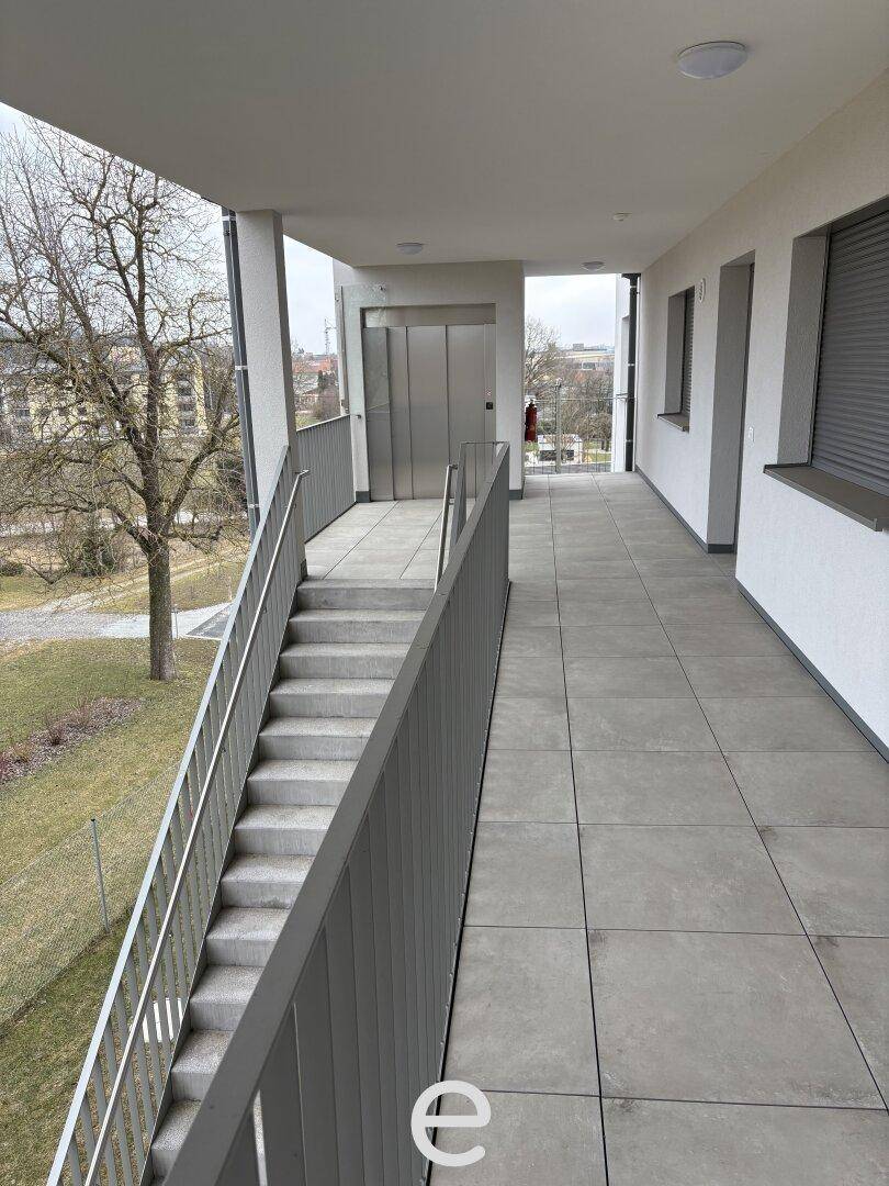Außenflur mit Treppenaufgang und Aufzug in einem modernen Wohngebäude.