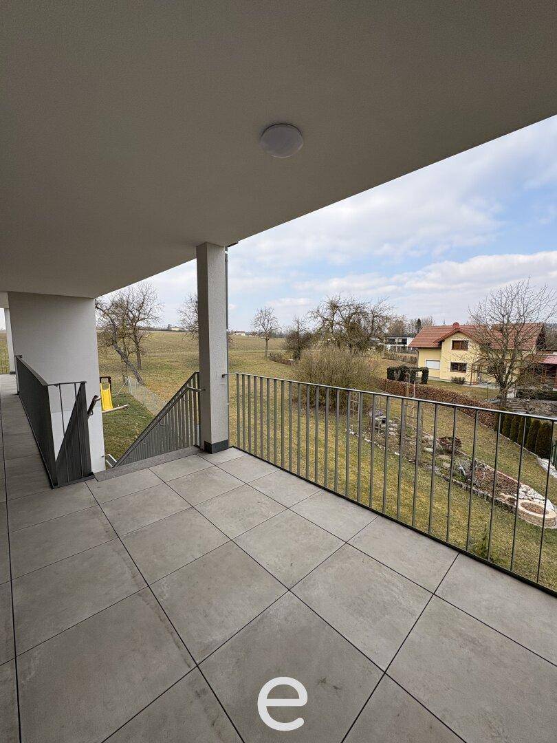 Geräumiger Balkon mit Fliesenboden und weitem Blick über die ländliche Umgebung.