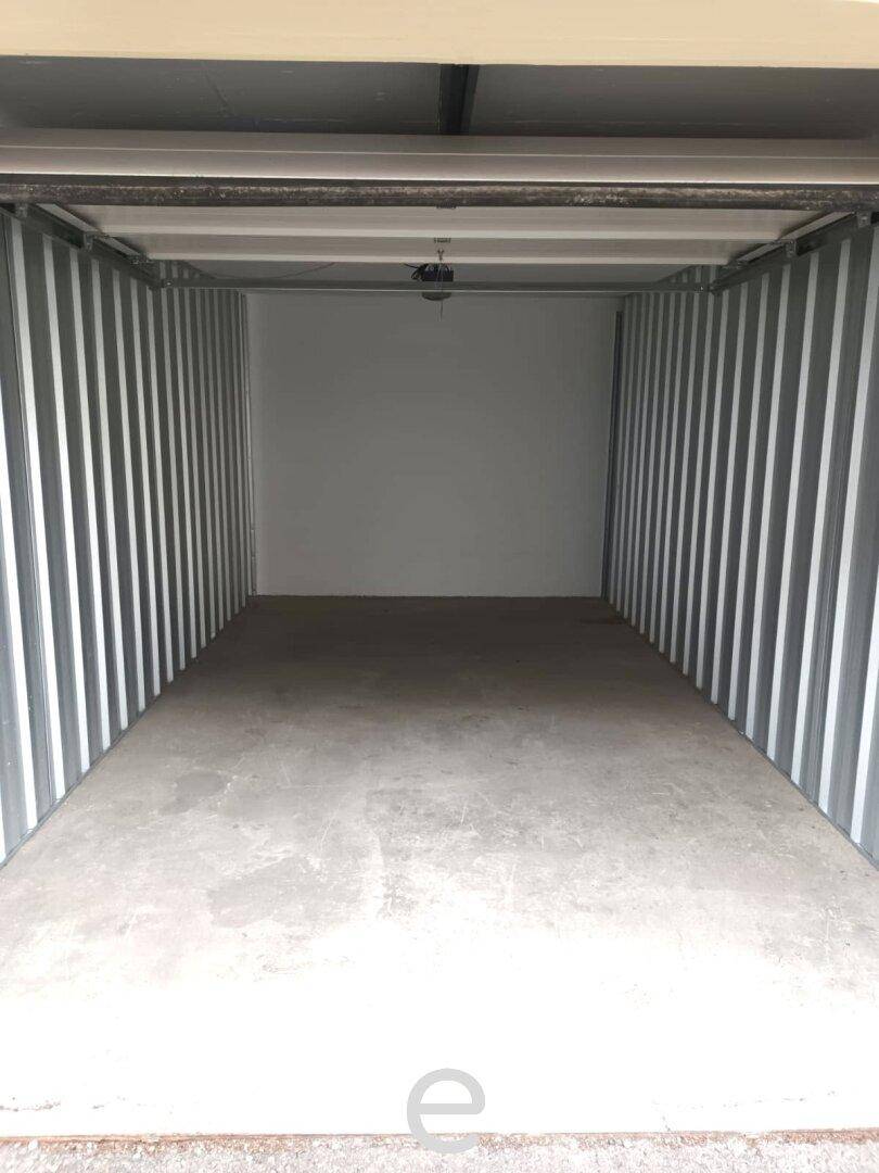 Leere, saubere Garage oder Lagerraum mit Betonboden und stabilen Metallwänden.