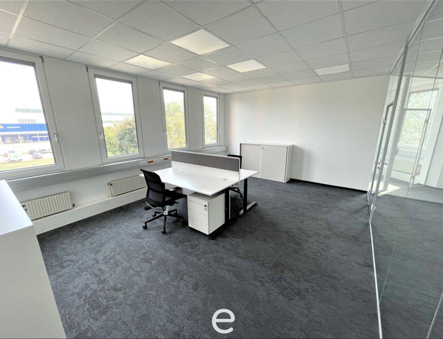 Einzelbüro mit großzügigen Fenstern, einem modernen Schreibtisch und viel Stauraum.