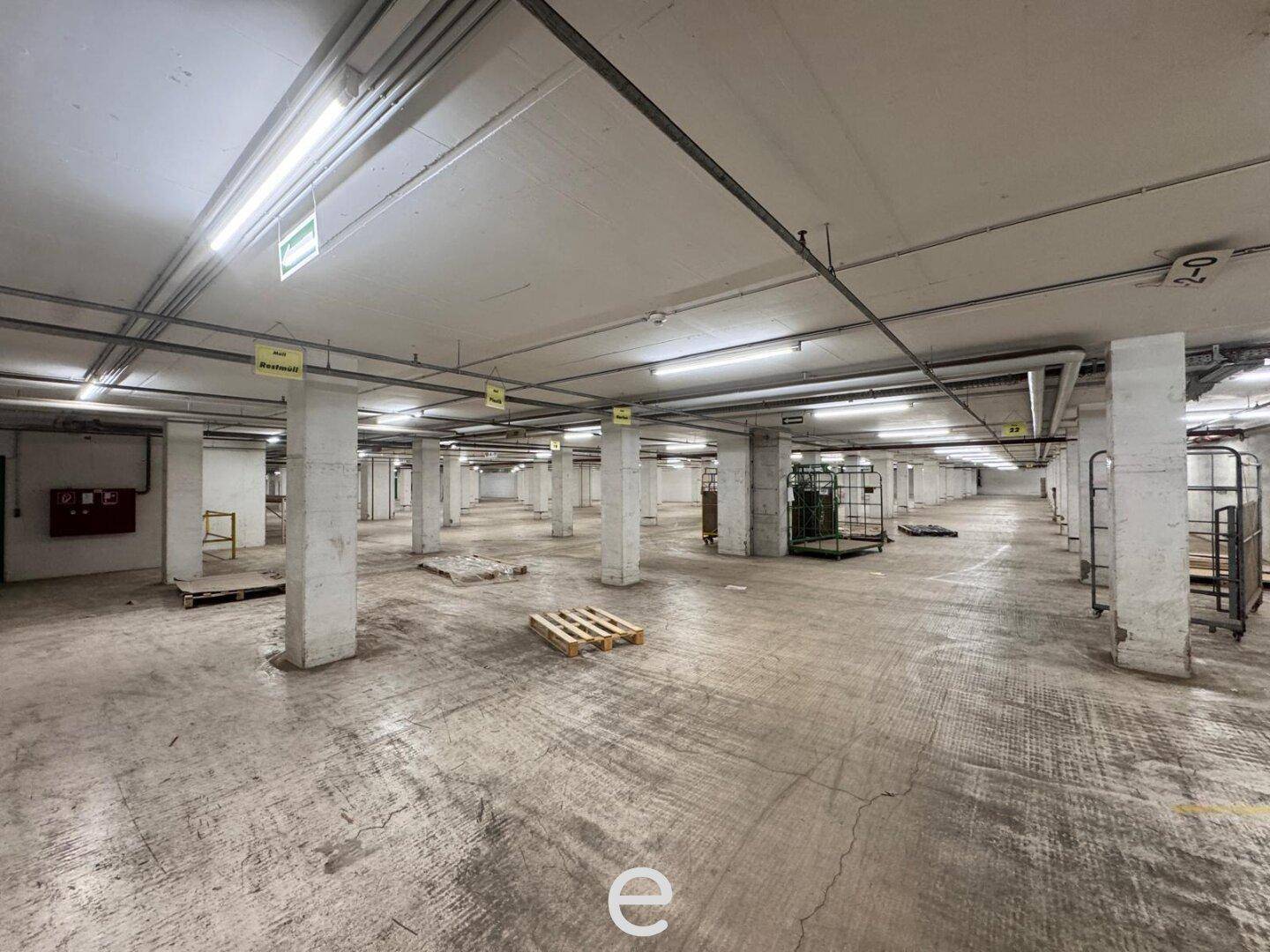 Weitläufige Tiefgarage mit vielen Säulen und Betonboden, gut beleuchtet und geräumig.
