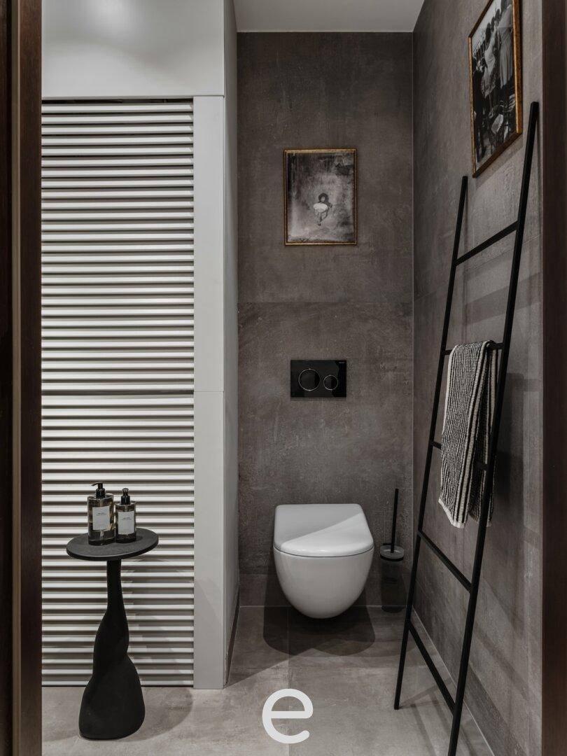Modernes Gäste-WC mit dunklen Fliesen, wandhängender Toilette und stilvoller Dekoration, sehr elegant.