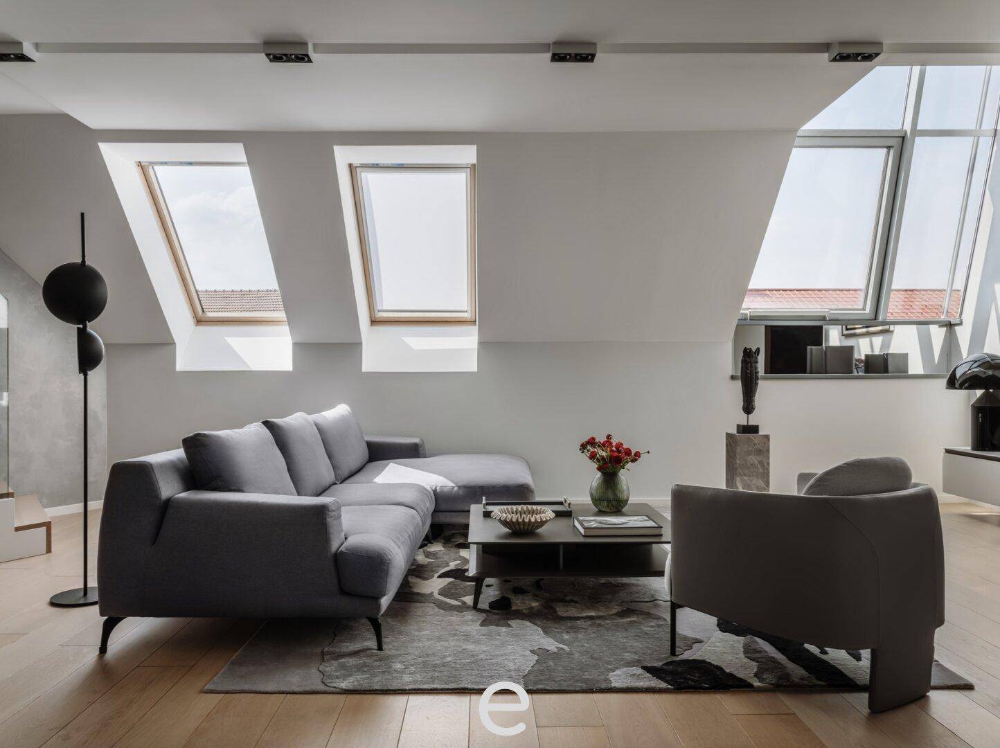 Modernes Wohnzimmer mit Dachschrägen, gemütlichem Ecksofa und großen Dachfenstern für viel Licht.