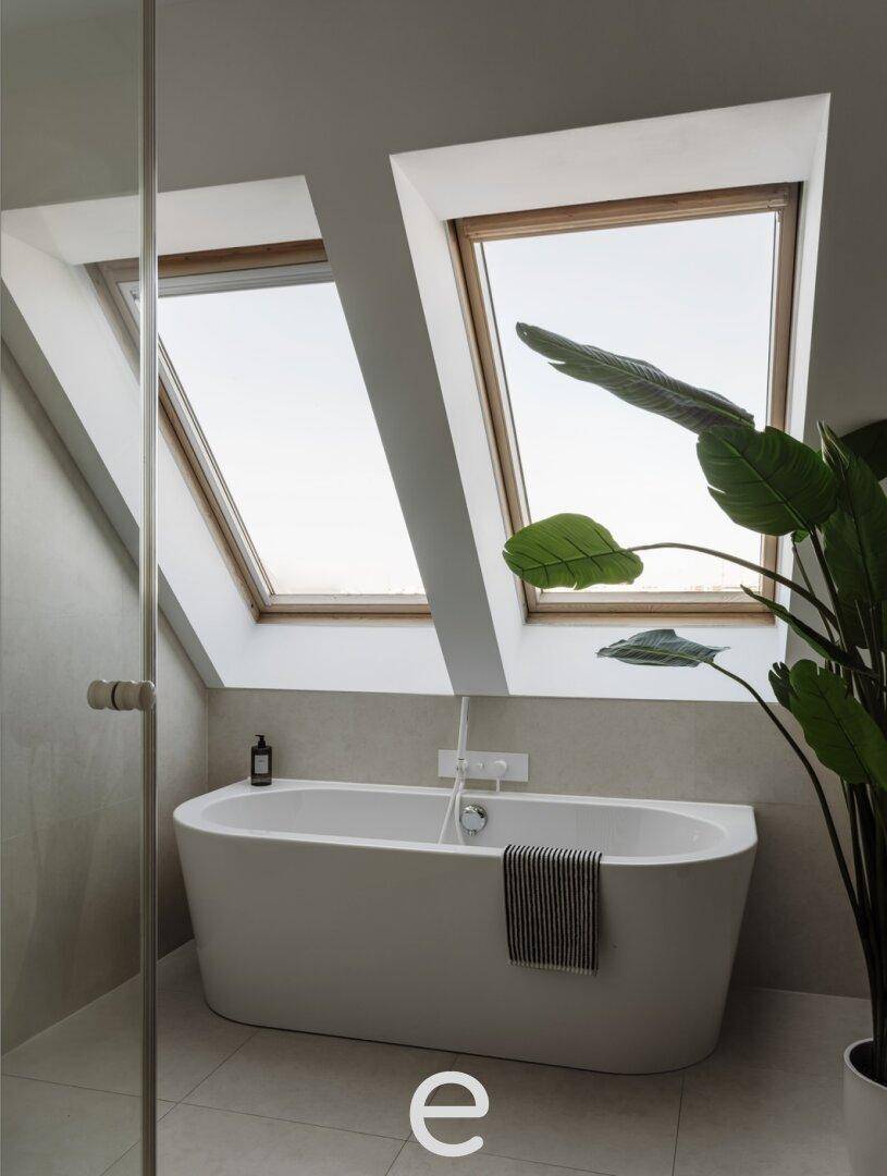 Modernes Badezimmer mit freistehender Badewanne, Dachfenstern und viel Tageslicht, eine Oase der Entspannung.