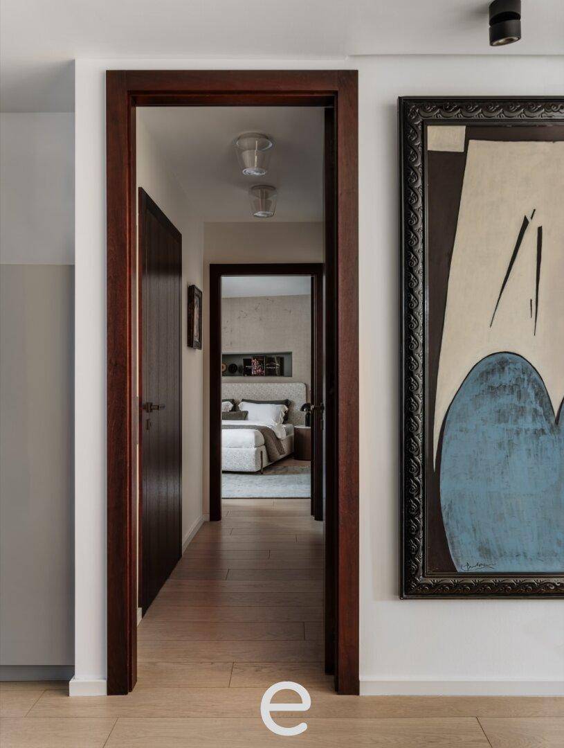 Heller Flur mit Holzboden und Blick in ein Schlafzimmer am Ende des Ganges, sehr einladend gestaltet.